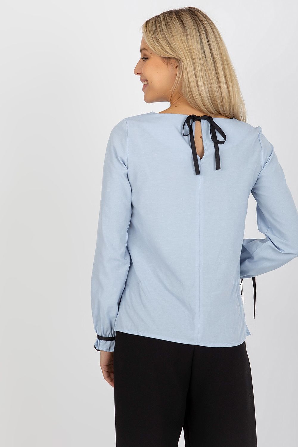 Elegant light blue cotton blouse with lace accents, showcasing a fashionable back tie closure, model smiling gracefully.