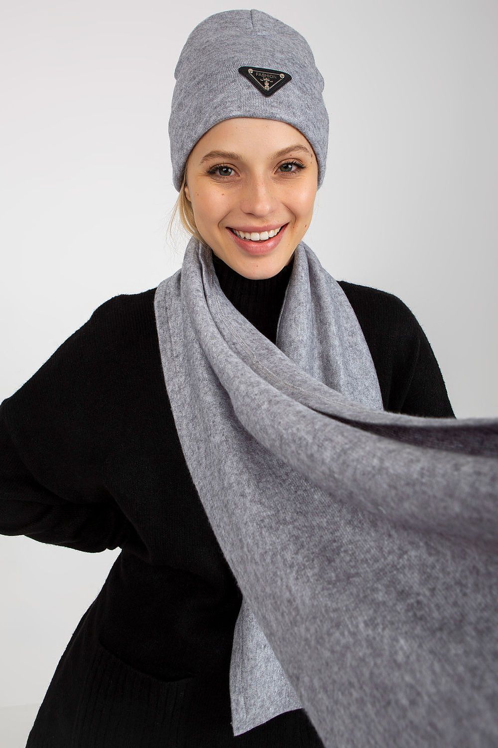 Close-up portrait of a radiant model donning a stylish grey Angora and spandex winter set, including a hat and a flowing scarf. The model’s joyful expression enhances the luxurious feel of the ensemble.