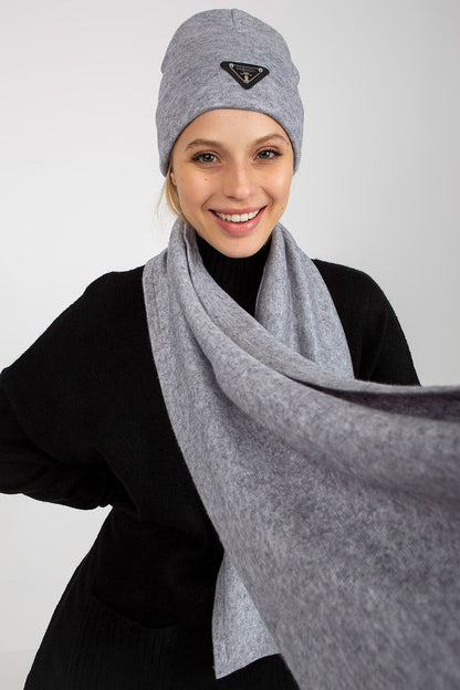 Close-up portrait of a radiant model donning a stylish grey Angora and spandex winter set, including a hat and a flowing scarf. The model’s joyful expression enhances the luxurious feel of the ensemble.