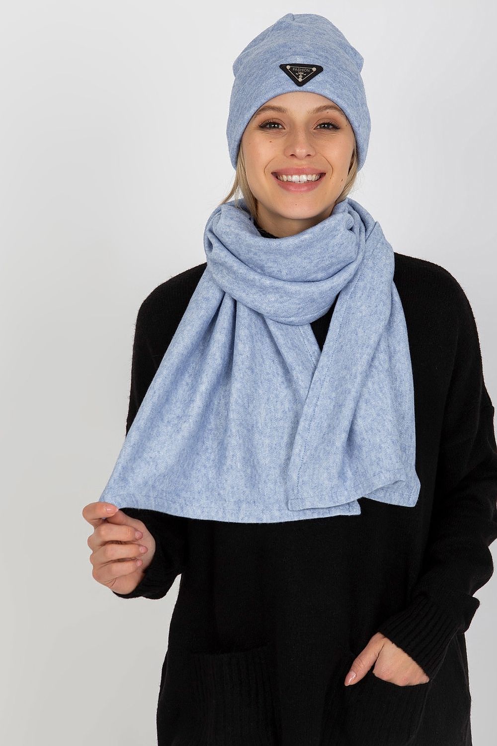 Charming woman smiling while showcasing a light blue luxurious angora and spandex winter set, including a hat and scarf.
