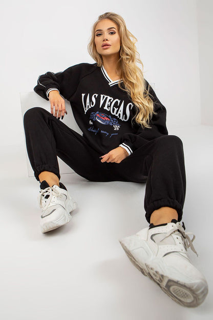 Chic black cotton blend sweatshirt set featuring a heart neckline and stylish tie waist pants, ideal for casual elegance. The model exudes confidence while sitting gracefully.