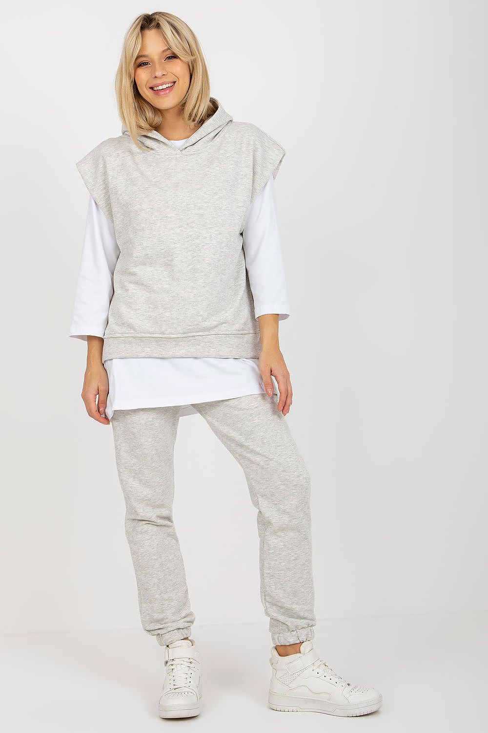 Sophisticated light grey 3-piece sweatsuit ensemble consisting of a stylish sleeveless hoodie and long pants, complemented by luxurious white sneakers for a modern look.
