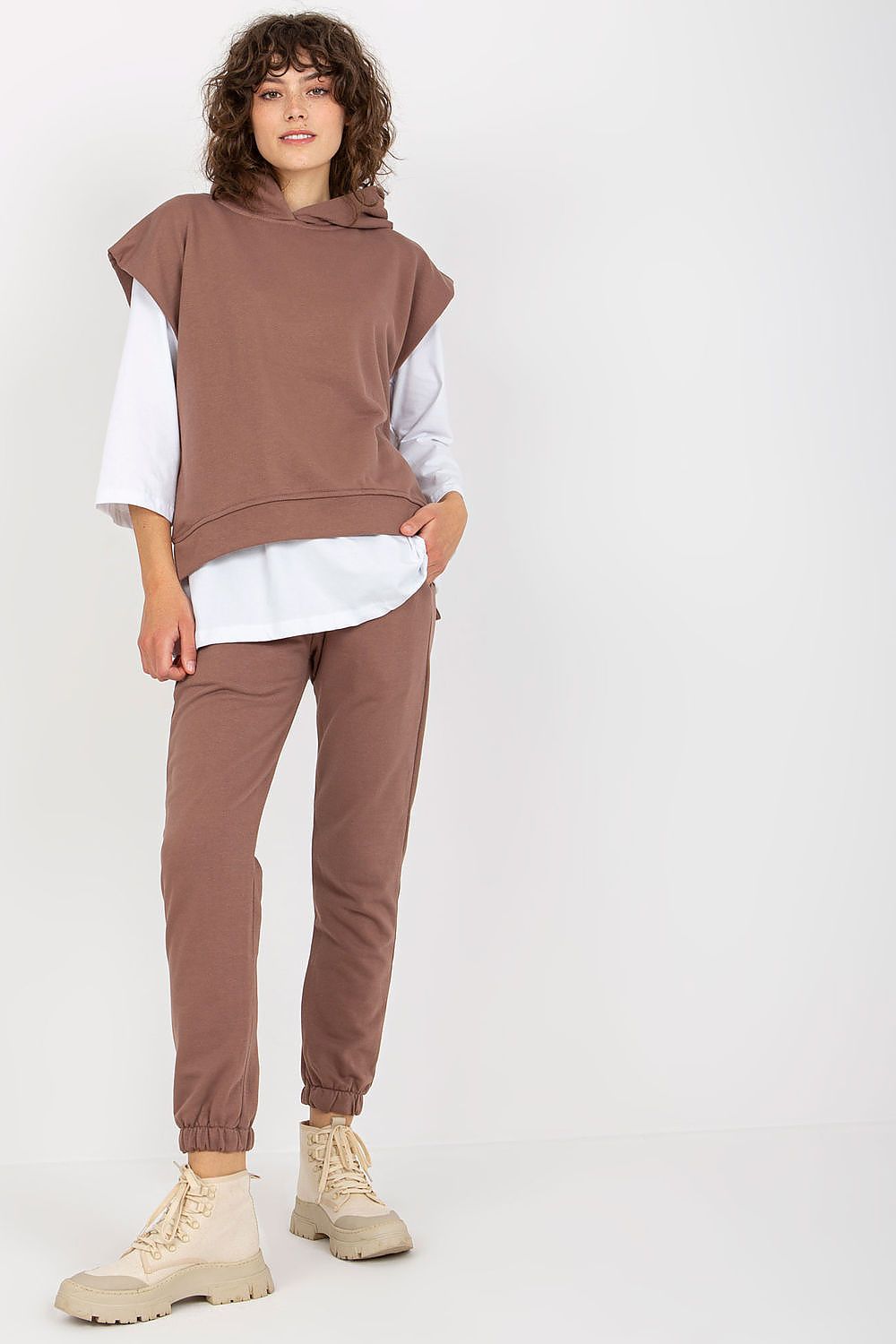 Chic model in a luxurious brown sweatsuit set, elegantly layered with a long-sleeve blouse, demonstrating contemporary style and finesse in casual fashion.