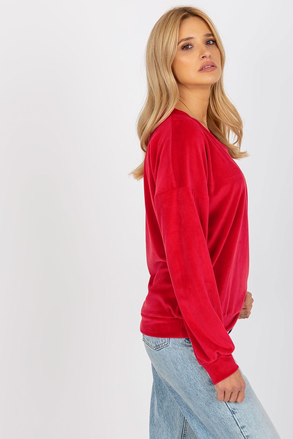 Side view of a red velour women's sweatshirt accentuating its relaxed fit and chic heart neckline.