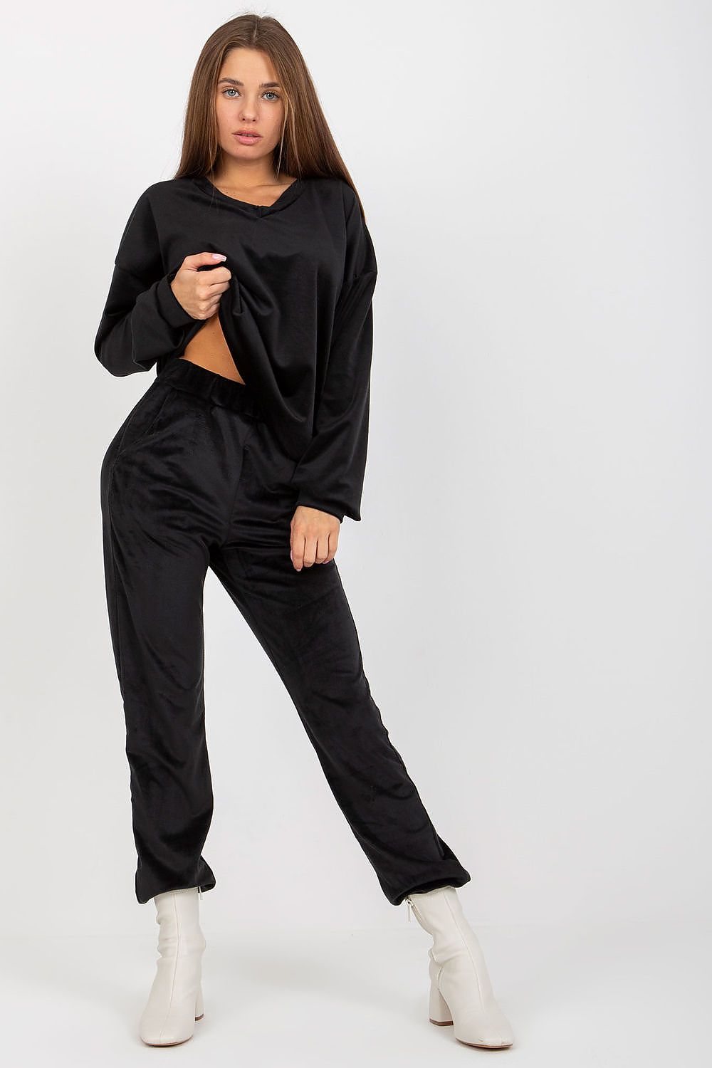 Fashionable women's black velour set, showcasing a relaxed sweatshirt and stylish trousers paired with elegant white ankle boots.