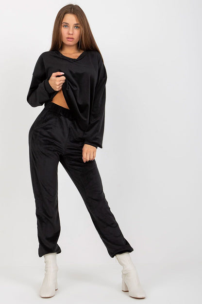 Fashionable women's black velour set, showcasing a relaxed sweatshirt and stylish trousers paired with elegant white ankle boots.