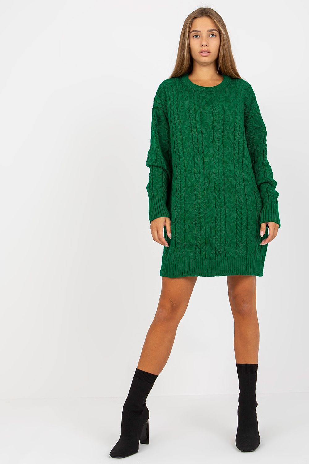 Model wearing an elegant long-sleeved green knit sweater by Rue Paris, showcasing a textured cable knit design, perfect for stylish layering over leggings.