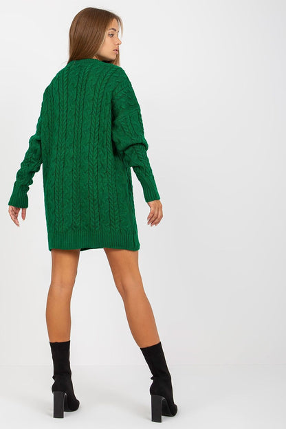 Back view of a model in a chic green cable knit sweater by Rue Paris, highlighting the sweater's generous length and sophisticated texture, perfect for pairing with leggings.