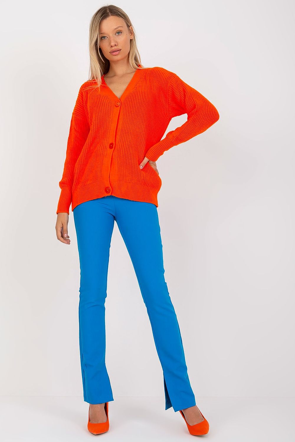 Elegant Rue Paris Women's acrylic button-closure cardigan in vibrant orange, paired with chic blue slim-fit trousers and high heels, showcasing a stylish autumn look.