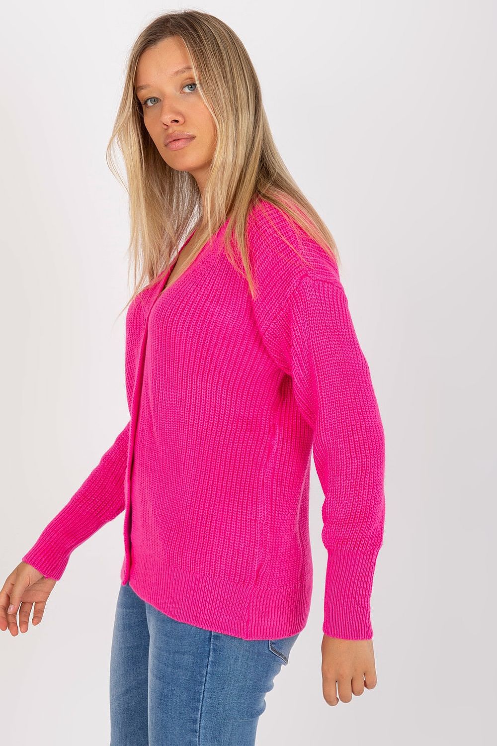 A woman elegantly styled in a vibrant pink long-sleeve cardigan, standing confidently, illustrating a blend of comfort and chic fashion.