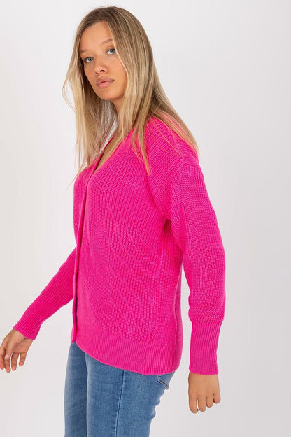 A woman elegantly styled in a vibrant pink long-sleeve cardigan, standing confidently, illustrating a blend of comfort and chic fashion.