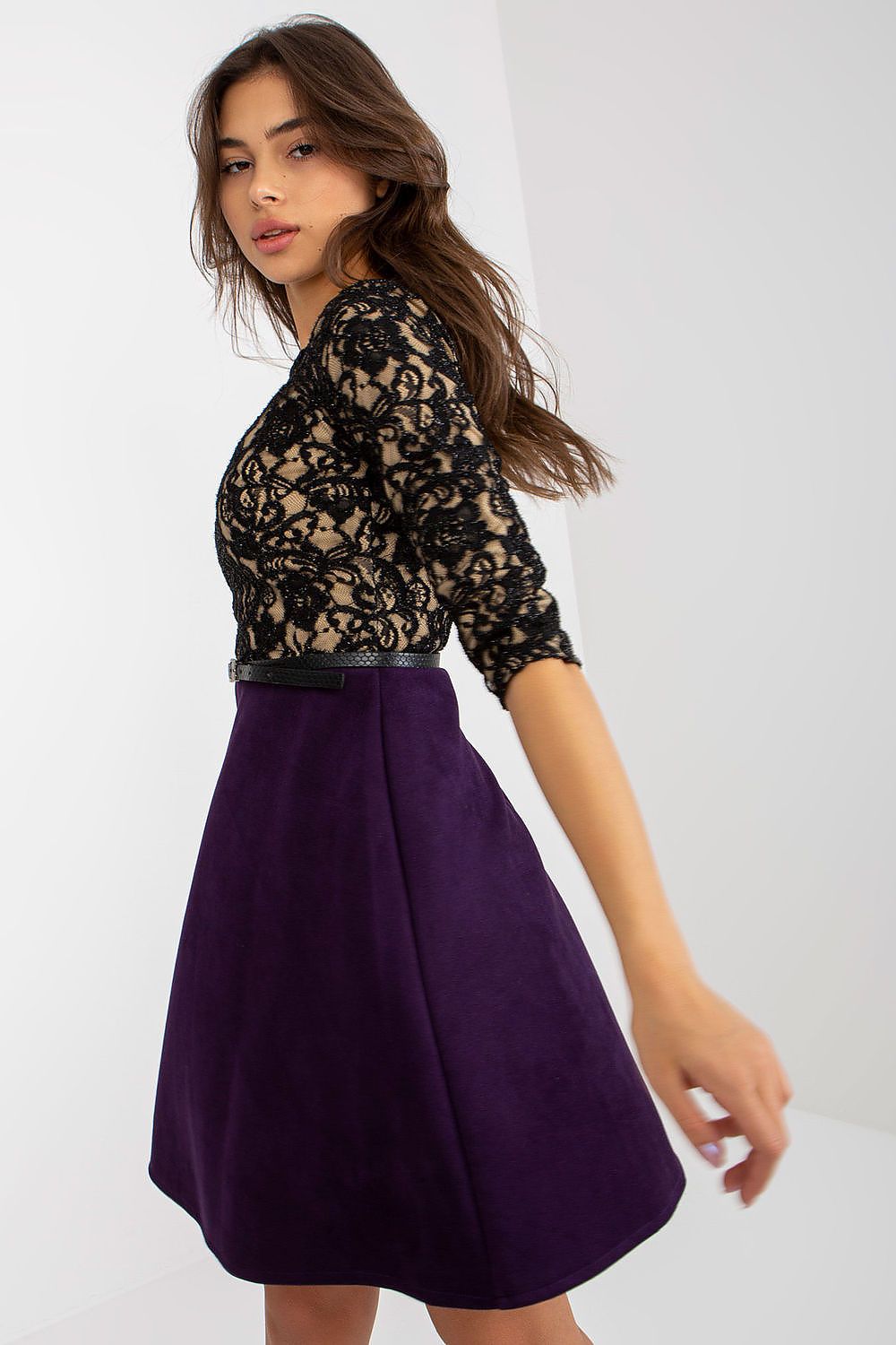 Chic side angle of a woman in a black lace evening dress featuring 3/4 sleeves and a rich purple skirt, exuding luxury and contemporary fashion.