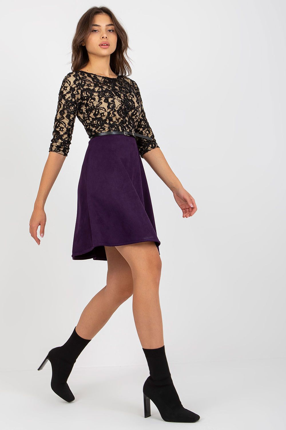 Confident front view of a woman modeling a 3/4 sleeve evening dress with a lace top and a flowing purple skirt, complemented by a fashionable buckled belt.