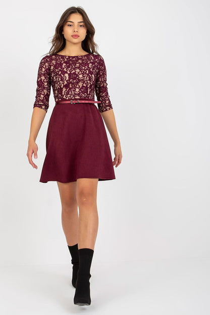 Graceful front view of a woman in a burgundy lace evening dress with 3/4 sleeves and a matching skirt, enhanced by a stylish belt, embodying luxury and refinement.