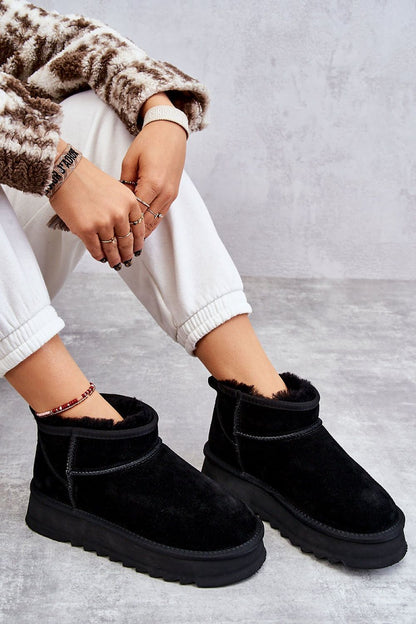Chic black snow boots designed with a warm fur lining, showcased alongside white joggers, exuding effortless winter elegance.