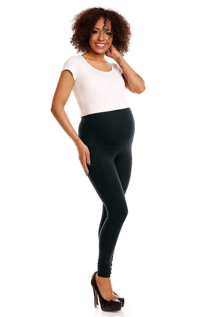Smiling pregnant model wearing sleek black maternity leggings, effortlessly combining elegance and functionality for the modern mum-to-be.