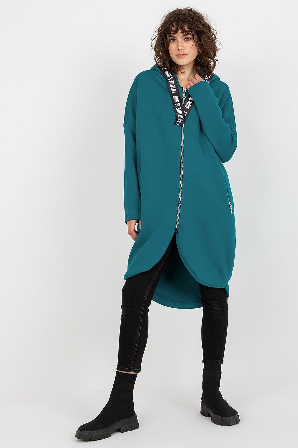 Elegant women's zippered hooded sweatshirt in a luxurious teal colour, featuring an extended cut, styled with black skinny jeans and ankle boots, perfect for a sophisticated casual look.