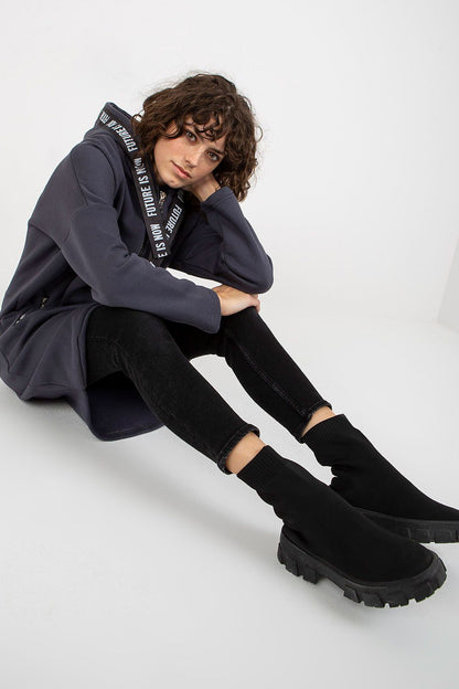 Fashionable luxury women's zippered hooded sweatshirt showcasing an extended cut and stylish zip pockets, paired with chic black jeans and edgy ankle boots.