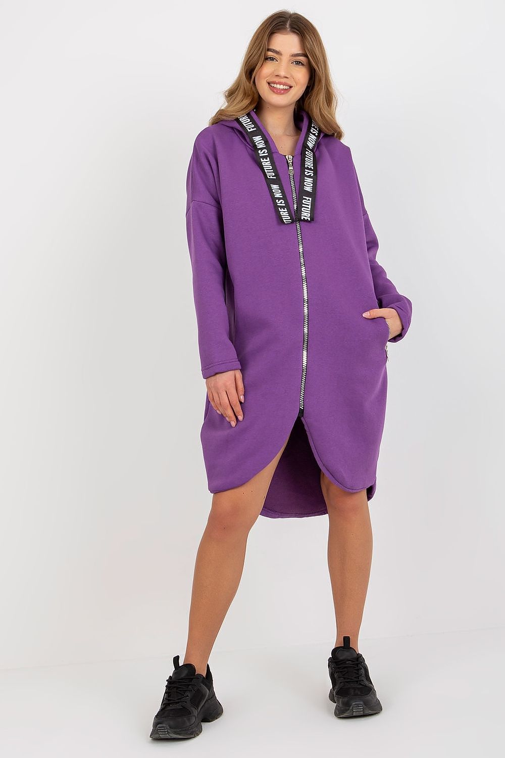 Stylish women's purple hooded sweatshirt with a front zipper and luxurious extended cut, complemented by casual yet fashionable footwear for an effortlessly trendy outfit.