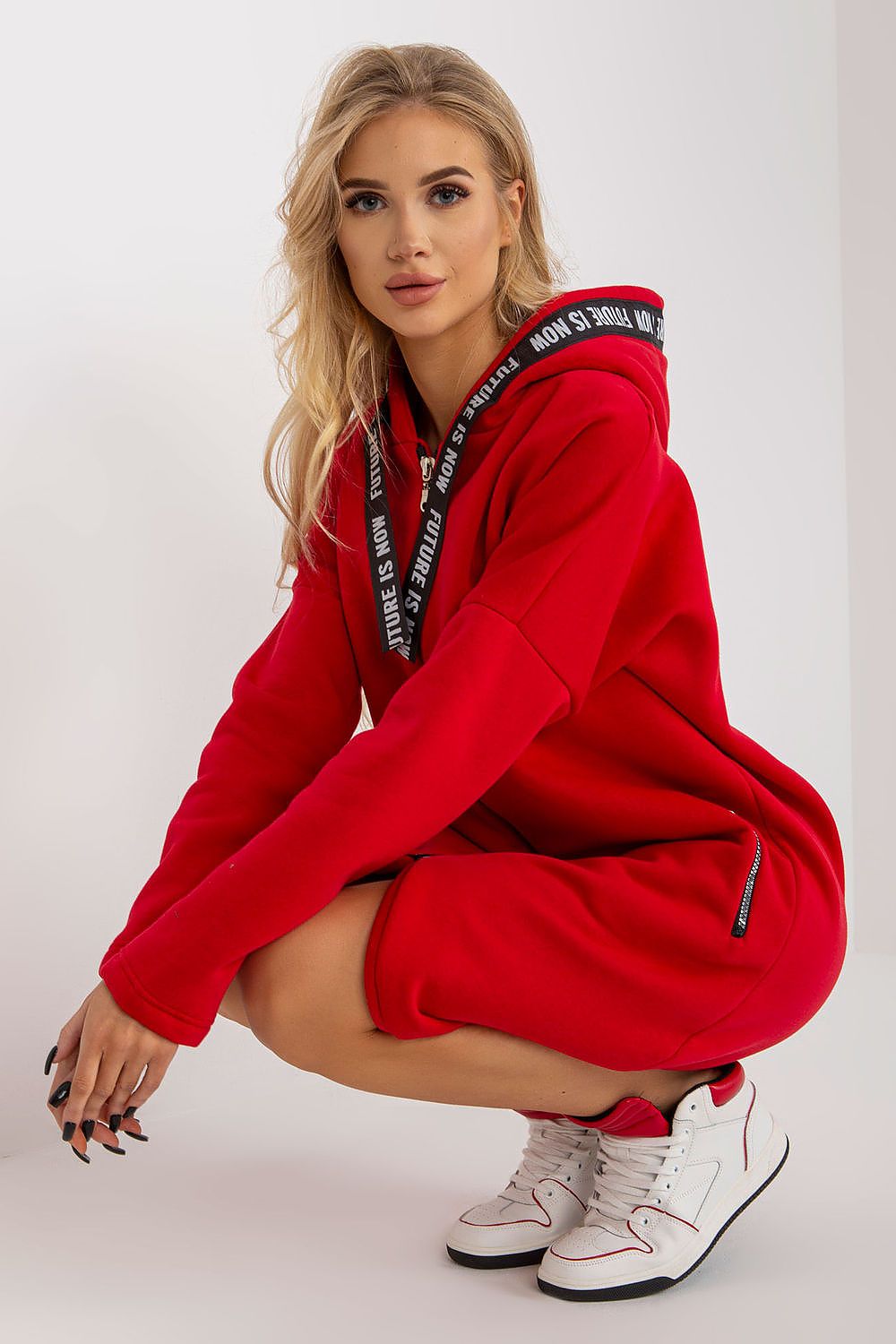Fashionable close-up of a red women's sweatshirt with a prominent hood and zippered pockets, ideal for chic everyday wear.