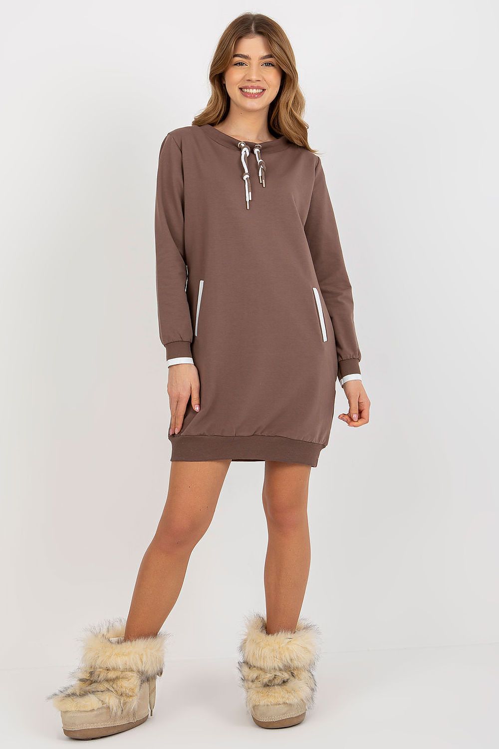 Sophisticated brown tracksuit dress modelled with a stylish attitude, featuring long sleeves and pockets, complemented by plush fur boots for a fashionable finish.