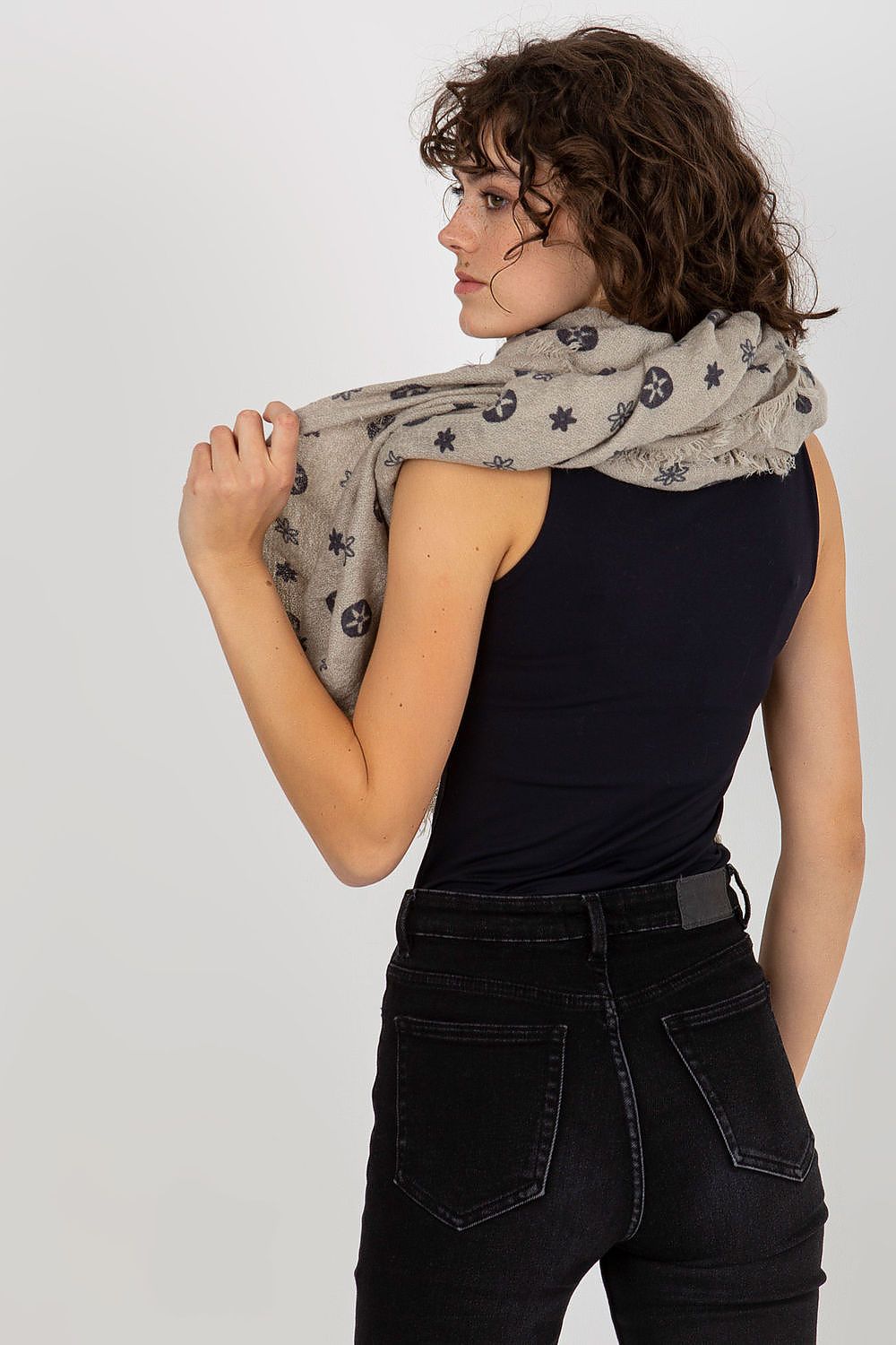 Elegant woman showcasing a luxury 100% acrylic neckerchief in a stylish pattern, draped gracefully over her shoulder. The scarf features intricate designs against a soft neutral background, complementing her chic black outfit.