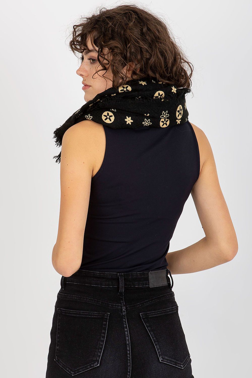 Back view of a stylish woman with curly hair, elegantly sporting a luxurious black neckerchief with distinctive designs. The scarf is draped around her neck, showcasing its chic flair.