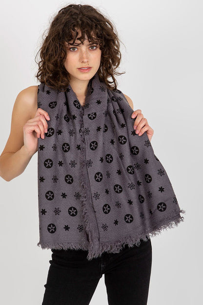 Chic woman holding a luxurious grey neckerchief, embellished with sophisticated patterned details. The scarf adds an air of refined elegance to her ensemble, highlighting its fashionable versatility.