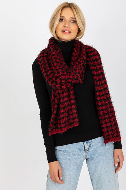 Elegant female model wearing a luxurious knitted acrylic shawl scarf in black and red, styled with a fitted black turtleneck and light jeans, showcasing warmth and sophistication.