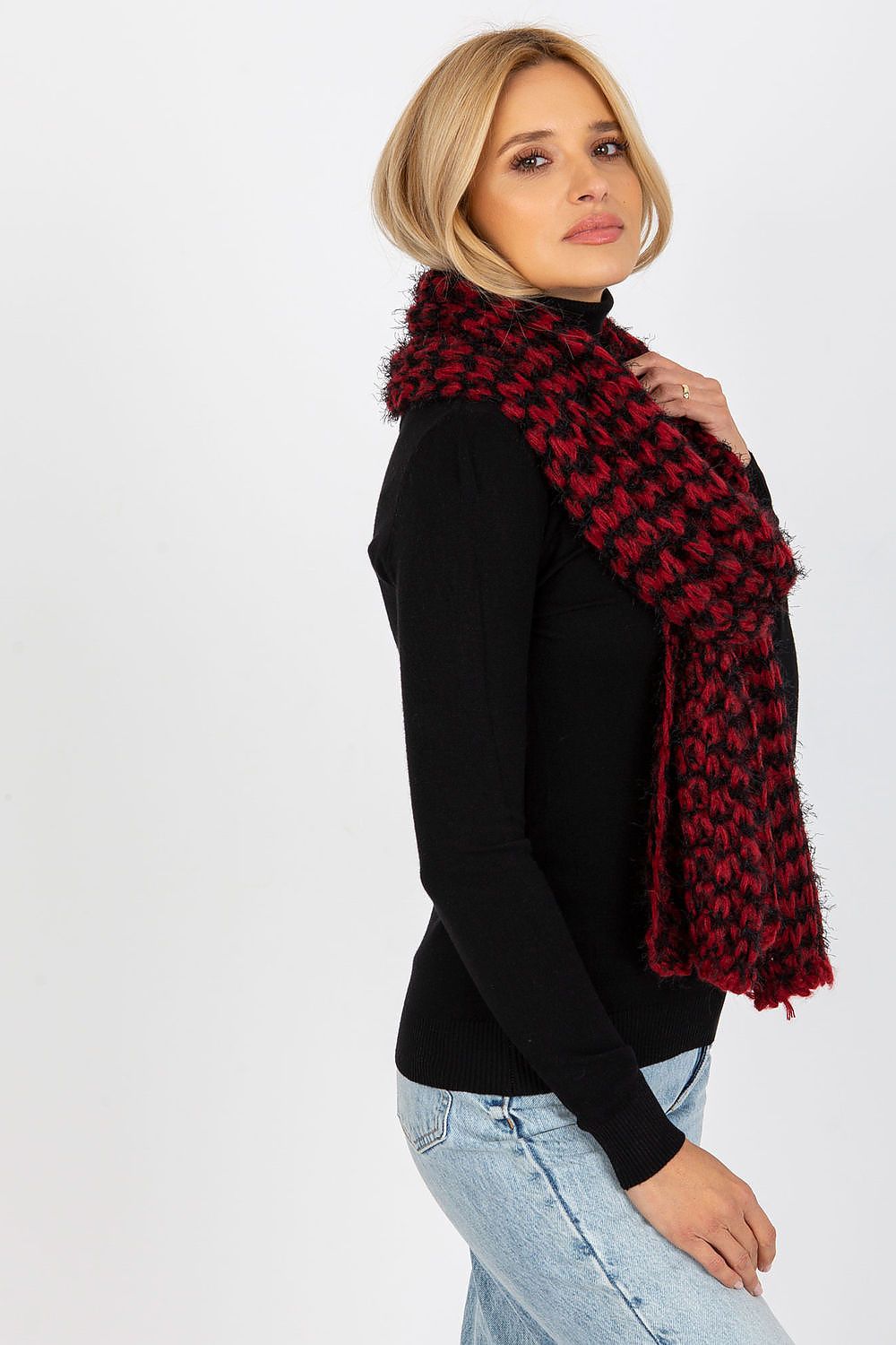 Chic side view of a stylish woman draped in a plush red and black knitted scarf, perfectly complementing her casual black sweater and exuding classic elegance.