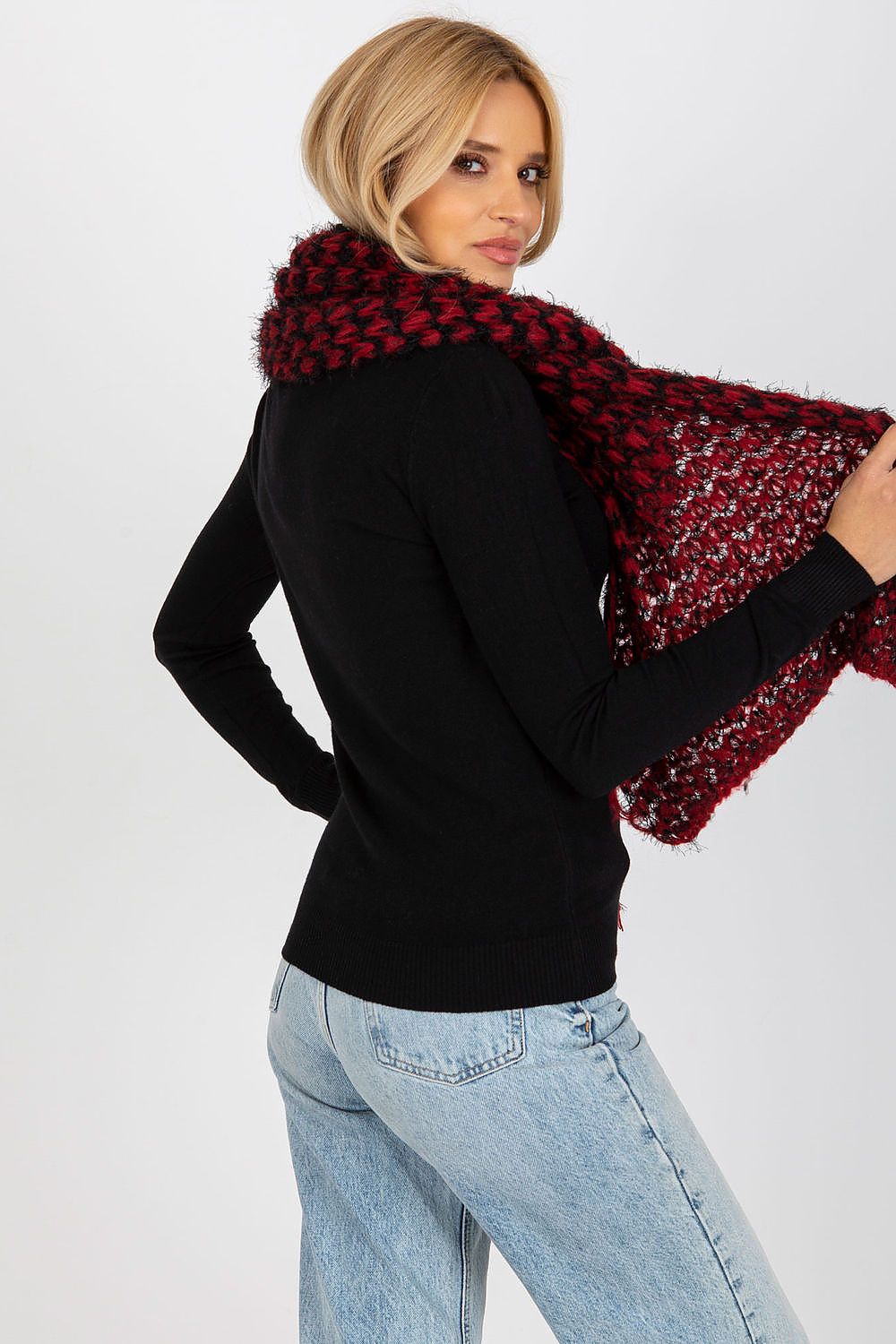 Sophisticated back view of a woman wearing a warm knitted scarf in rich black and red hues, paired with a form-fitting black top, epitomising modern luxury and style.