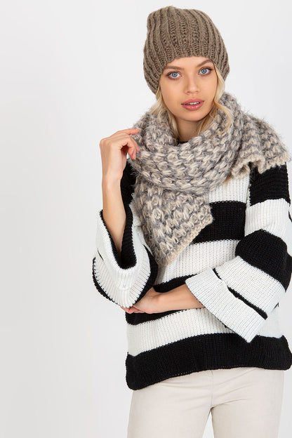 Fashionable model wearing a beige knitted beanie paired with a luxurious scarf, highlighting its textured pattern and warmth.