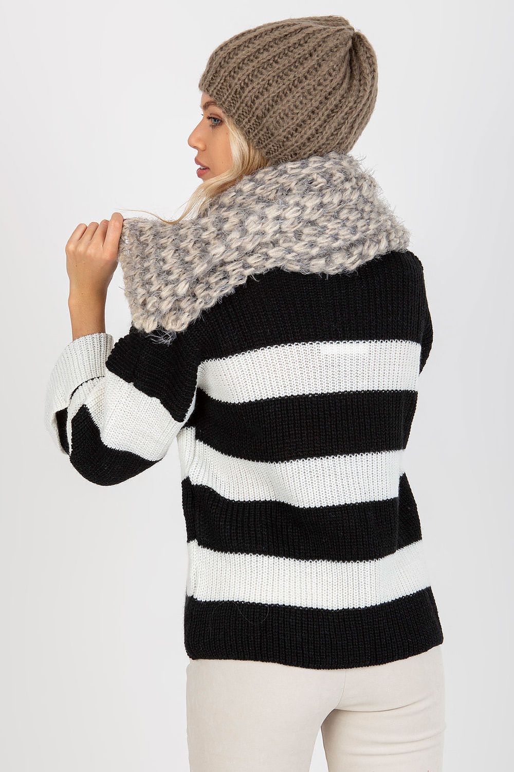 Elegant woman showcasing a knitted shawl scarf with a stylish beanie, exuding sophistication in a black and white striped sweater.