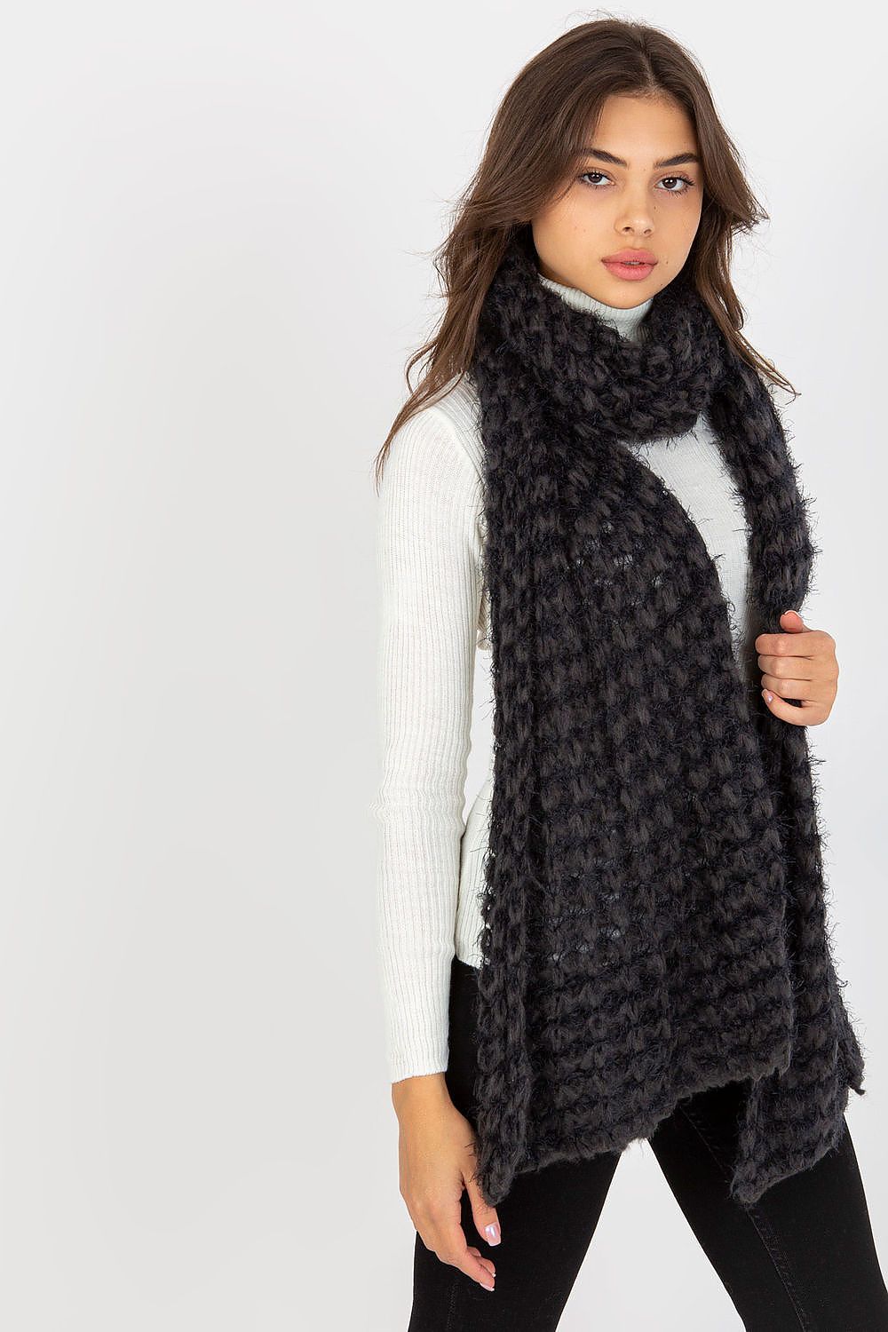 Sophisticated young woman in a black knitted scarf, subtly styled with a white long-sleeved top for a refined autumn look.