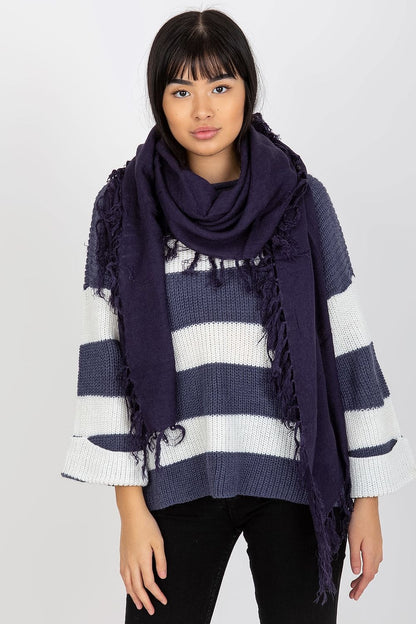 Stylish woman adorned in a rich navy shawl scarf with tassels, contrasted beautifully against a striped sweater, embodying contemporary luxury.