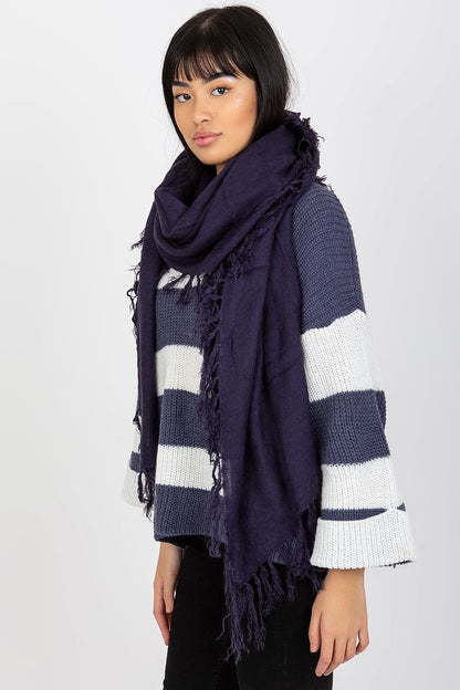 Graceful woman showcasing a deep navy tasselled shawl scarf, elegantly layered over a striped sweater, highlighting luxury fashion.