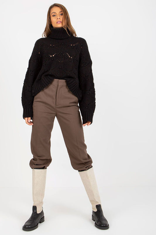 Luxury black openwork turtleneck sweater with wide sleeves, styled casually with tailored brown trousers and elegant black boots on a model.
