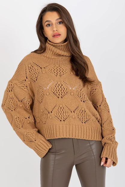 Model showcasing a luxurious camel openwork turtleneck sweater, featuring wide sleeves, paired with fitted brown leather trousers for a chic, sophisticated look.