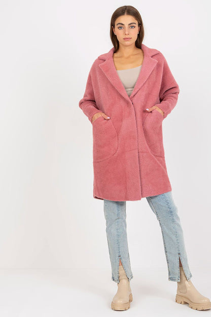 Elegant women's angora wool blend coat in soft pink, featuring long sleeves and slip pockets, styled with light jeans and chic boots.