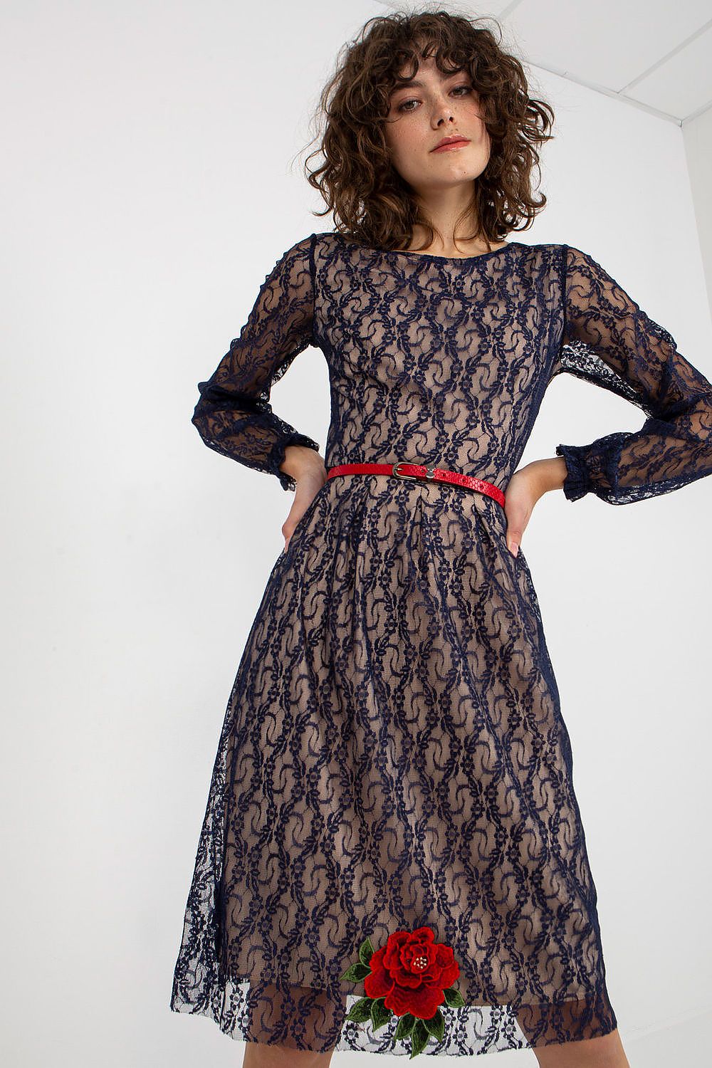 Elegant luxe lace evening dress with long sleeves, intricate floral embellishments, and a figure-flattering red belt, showcased against a minimalist backdrop for a sophisticated look.