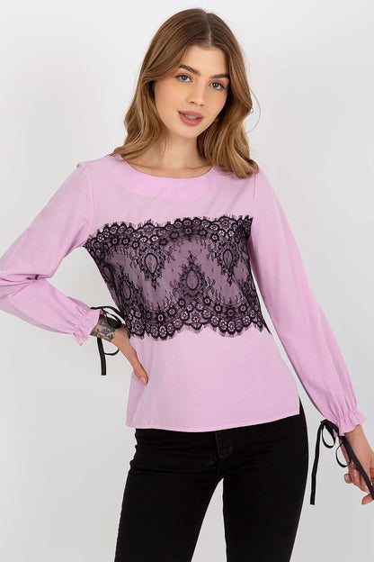 Sophisticated pink blouse with decorative black lace, perfect for any occasion, model posing confidently.