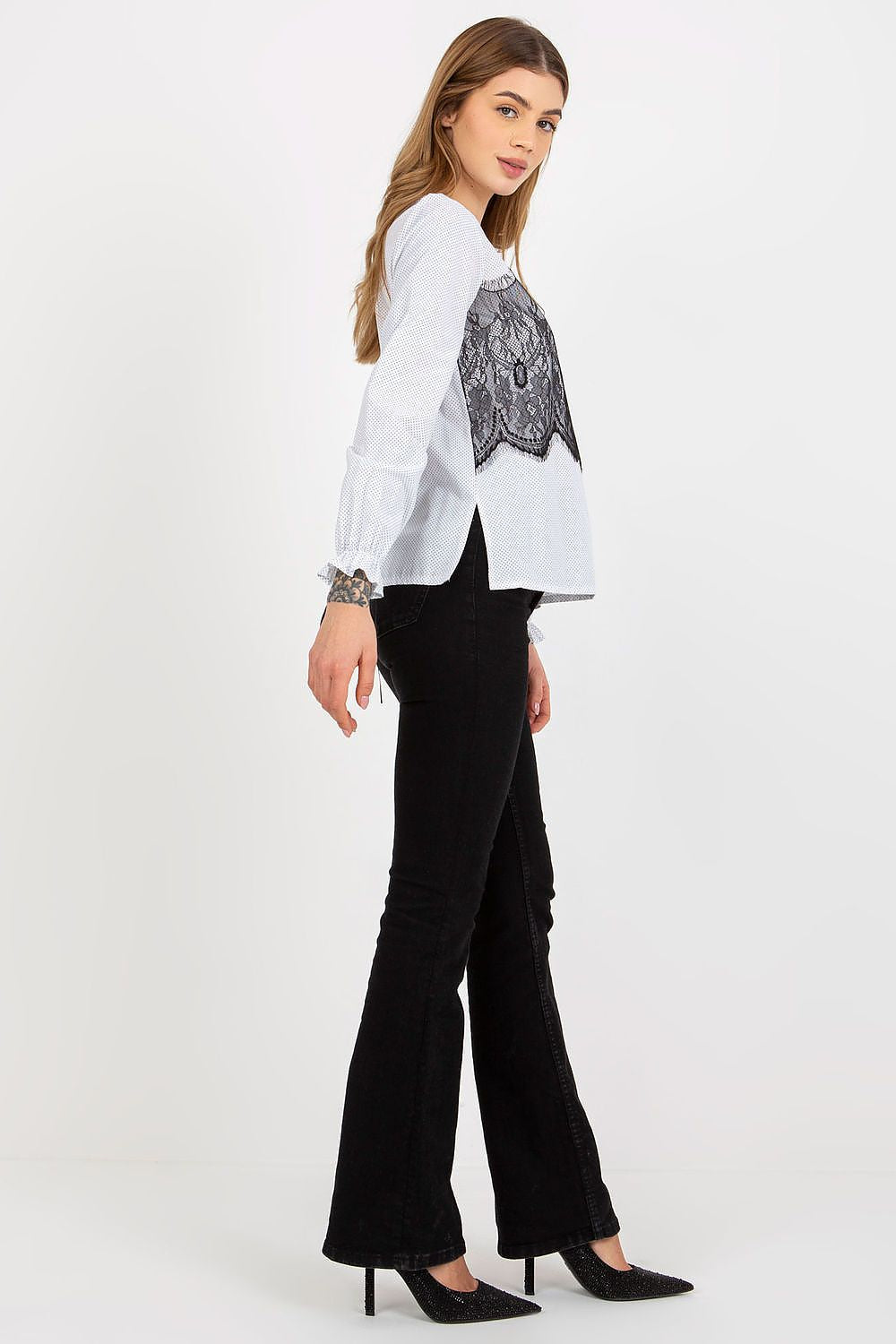 Fashionable side view of a white blouse with intricate black lace accents, complemented by chic black flare jeans, exuding luxury.