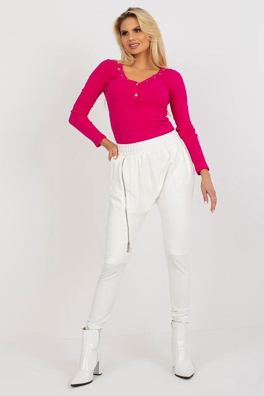 Chic woman in high waist white tracksuit trousers with zipper, paired with a vibrant pink long-sleeve top, exuding elegance and comfort.