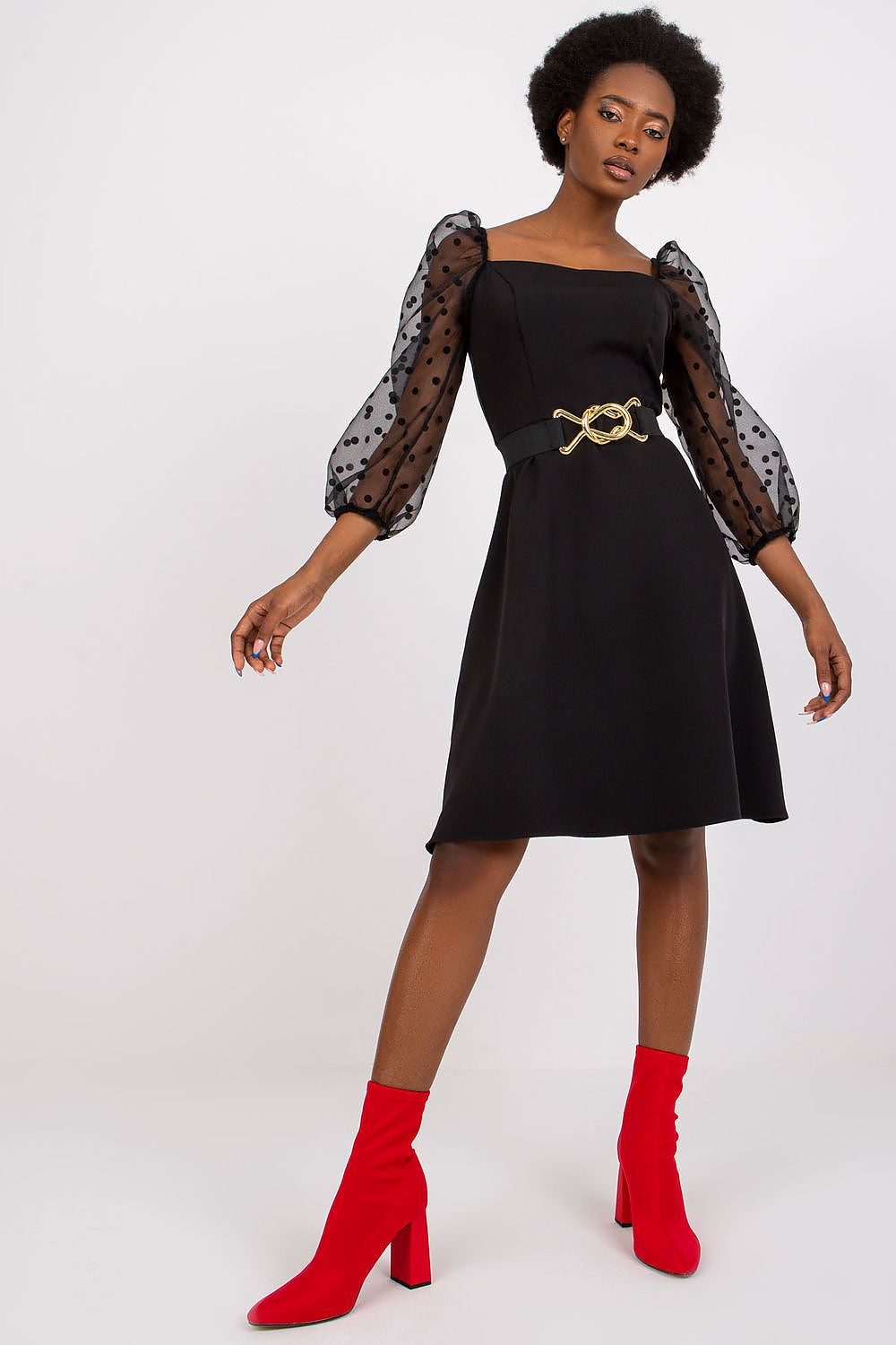 Luxurious black evening dress by Lakerta featuring elegant 3/4 sheer polka dot sleeves, a cinched waist with a stylish belt detail, and a refined covered zipper closure, complemented by vibrant red ankle boots.