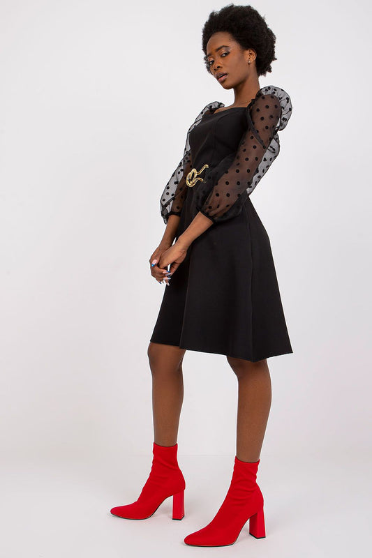 Sophisticated black dress with voluminous polka dot sleeves by Lakerta, elegantly styled with a chic belt accent, showcased with bold red heeled boots for a striking evening look.