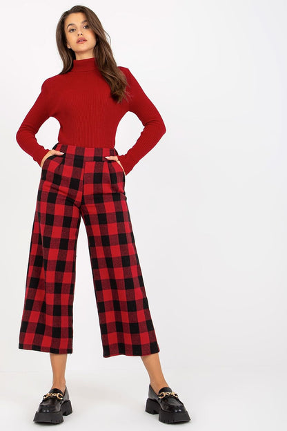 Chic and cosy, these red and black checkered trousers from Lakerta reflect luxury with their rich fabric and sophisticated styling, worn with a fitted turtleneck for an elegant ensemble.