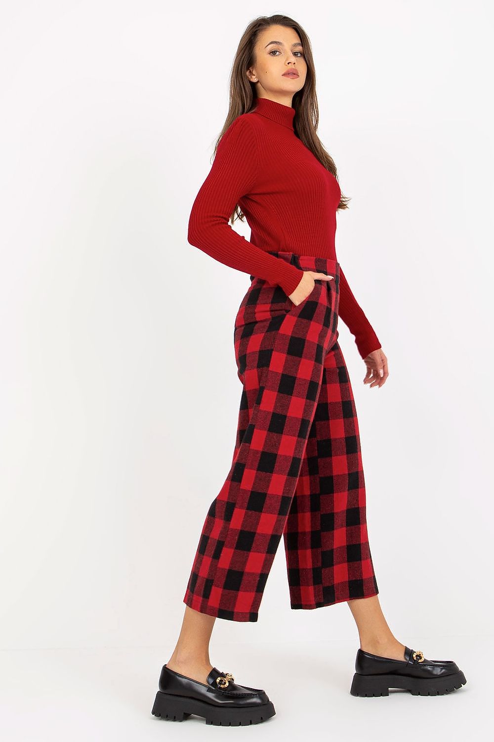 Elegant woman in a red ribbed turtleneck and checkered wool trousers, showcasing a stylish silhouette with slip pockets.