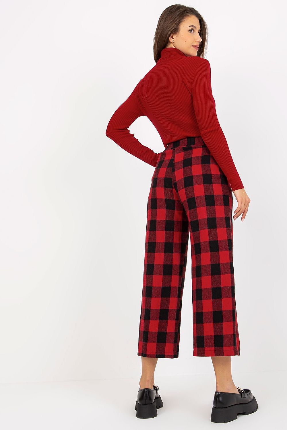 Sophisticated rear view of a lady in a red ribbed turtleneck and black-and-red checkered wool trousers, highlighting a flattering fit.
