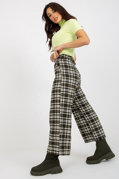 Stylish woman in a lime green turtleneck and checkered wool trousers, posing gracefully to emphasise a fashionable ensemble.