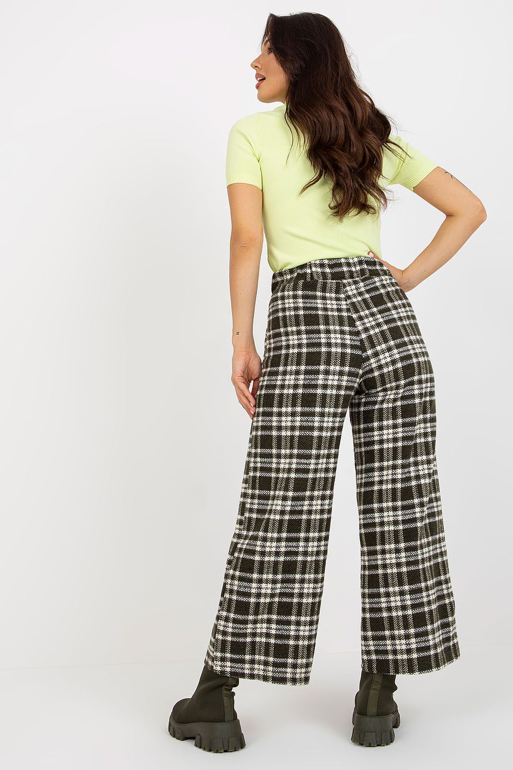 Elegant woman in checkered wool trousers, showcasing a chic back view, paired with a stylish light green top.